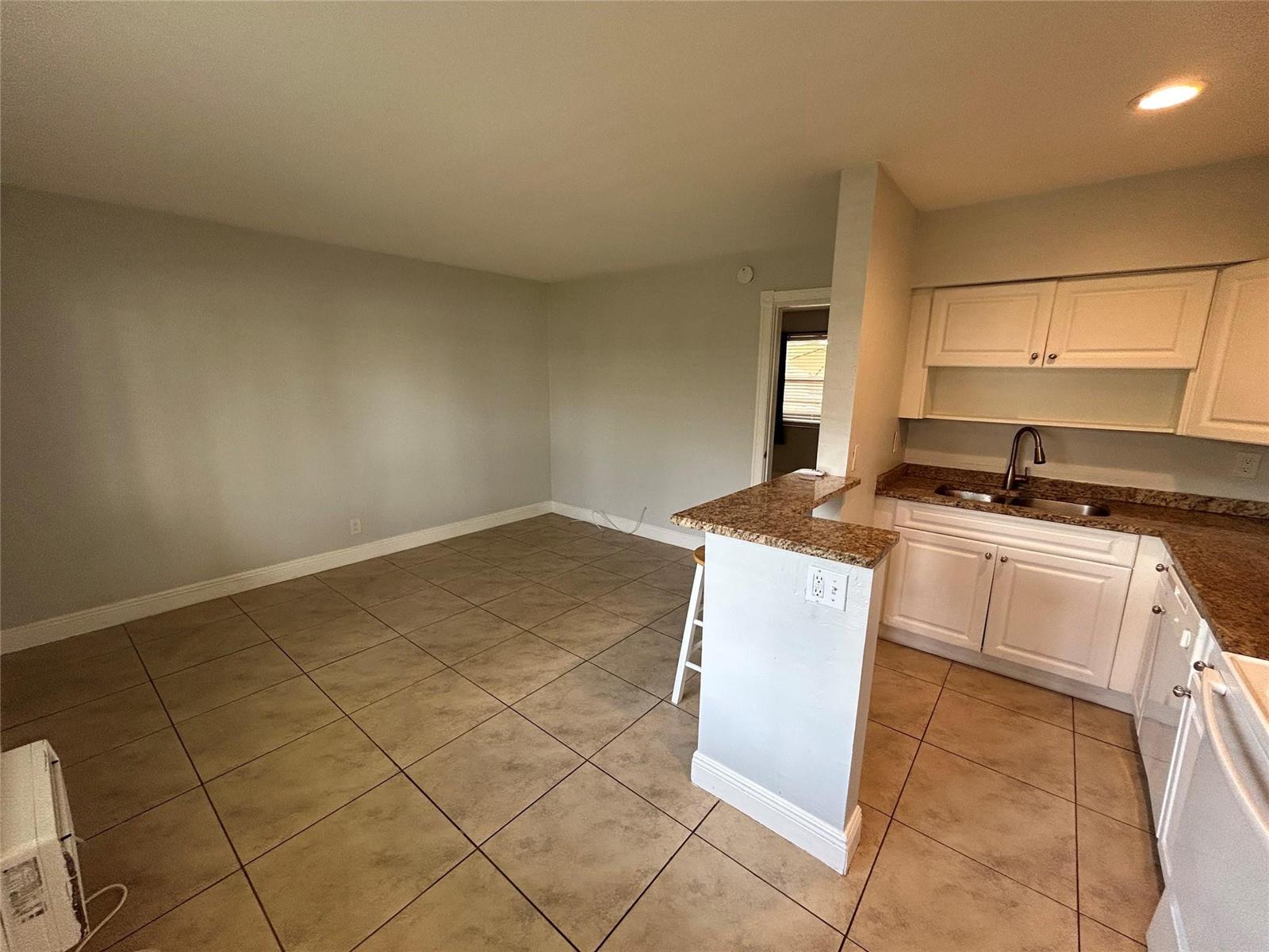 A kitchen with white cabinets and granite countertops opens to an adjacent tiled dining area — 921 NE 17th Avenue # 2, Fort Lauderdale FL 33304, FORT LAUDERDALE, FL