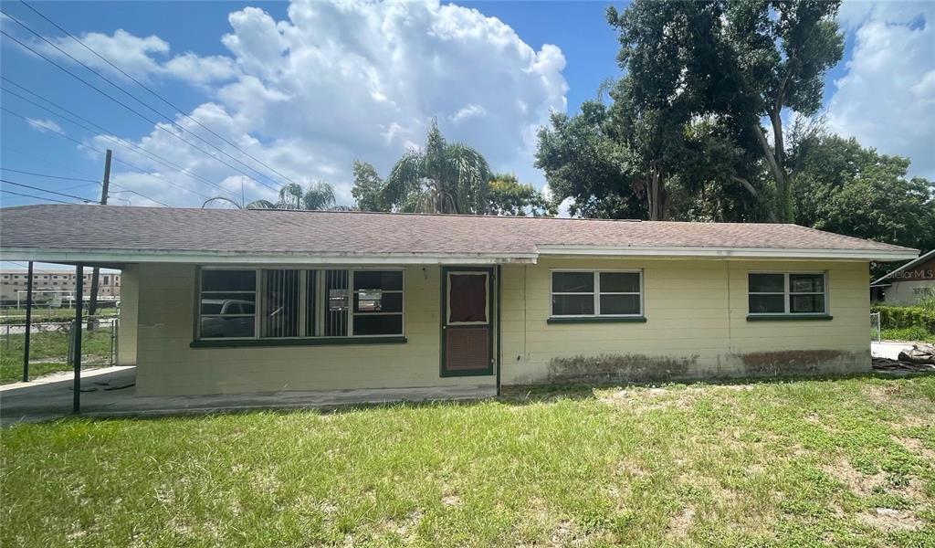 A single-story, light yellow house with a carport and a grassy front yard — 2033 VOLTAIRE STREET, LAKELAND, FL