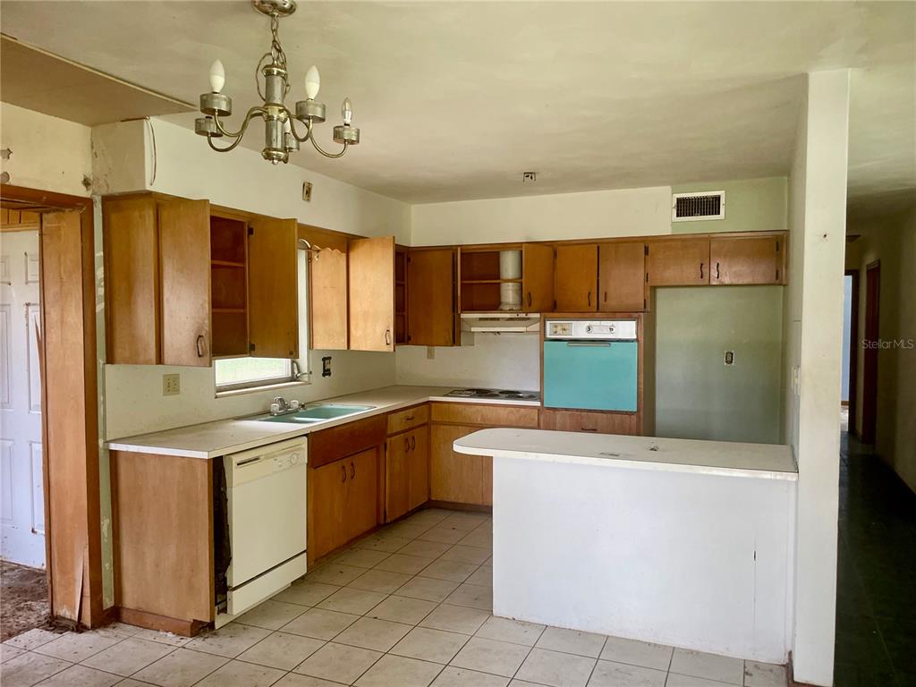 A kitchen with wood cabinets, a white dishwasher, a built-in oven, and tiled flooring — 2033 VOLTAIRE STREET, LAKELAND, FL