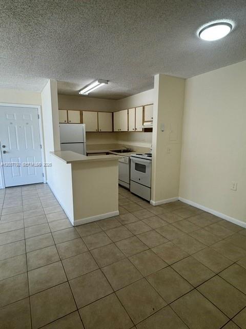 A kitchen features light-colored cabinets, a white refrigerator, and a tiled floor — 7030 NW 179th St # 104, Hialeah FL 33015, HIALEAH, FL