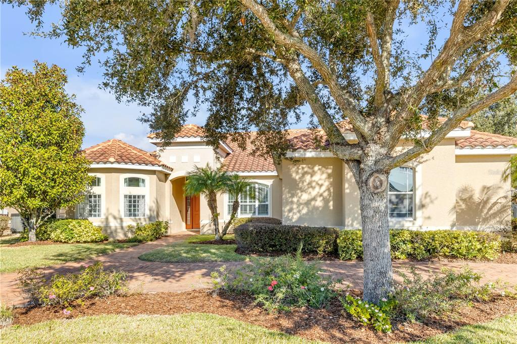 A single-story house with a tile roof, brick walkway, and a large tree in front — 3021 ISOLA BELLA BOULEVARD, MOUNT DORA, FL