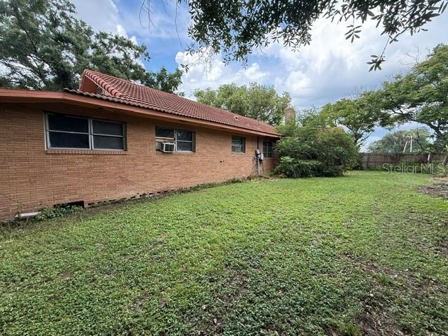 The exterior of a single-story brick house features a tiled roof and a grassy yard — 3011 S WIGGINS ROAD, PLANT CITY, FL