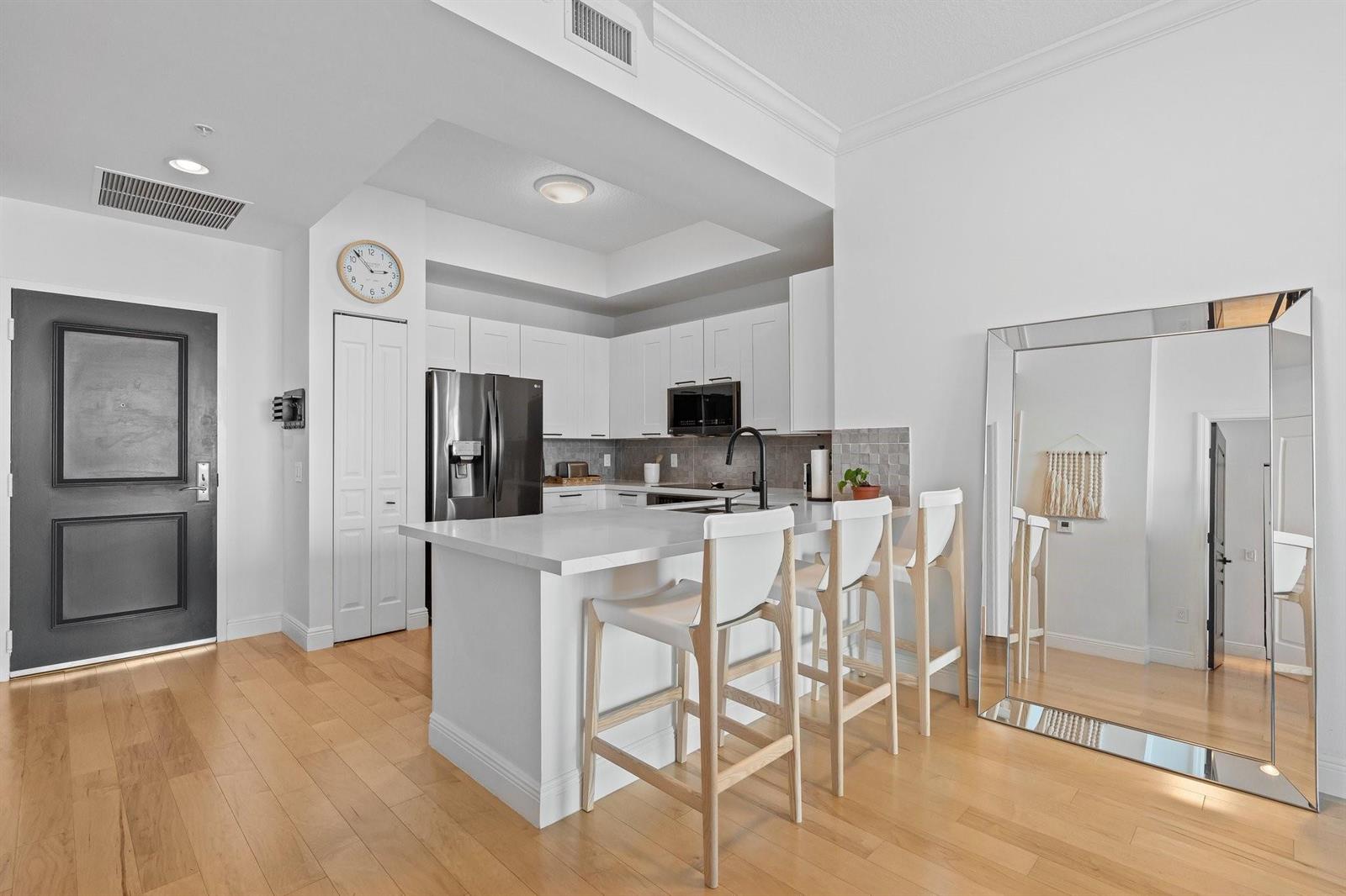 A kitchen features white cabinets, a quartz island with three bar stools, and hardwood floors — 350 SE 2nd Street # 2960, Fort Lauderdale FL 33301, FORT LAUDERDALE, FL