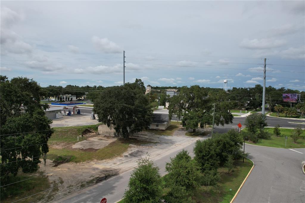 An elevated view of a vacant lot with trees, a small building, and a gas station — 138 W HERMOSA STREET, LADY LAKE, FL