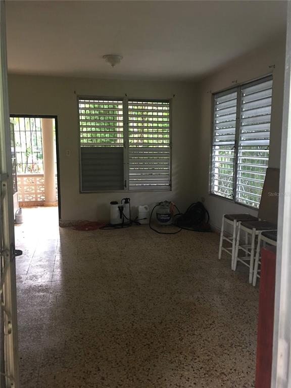 An interior room with terrazzo flooring, louvered windows, and a doorway leading to a porch — 352 BARRIO QUEMADO, MAYAGUEZ, PR