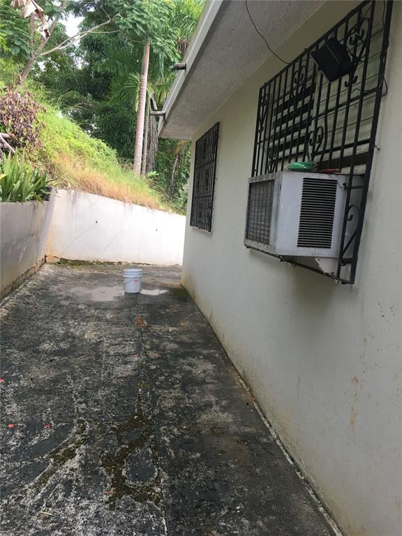 A side view of a house exterior with a window air conditioning unit and bucket — 352 BARRIO QUEMADO, MAYAGUEZ, PR
