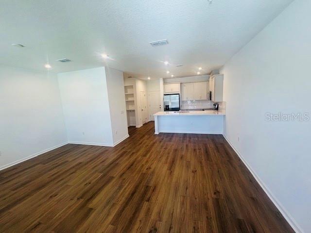 An open-concept living area features wood-look flooring and a kitchen with white cabinetry — 11525 STRAITS WAY, ORLANDO, FL