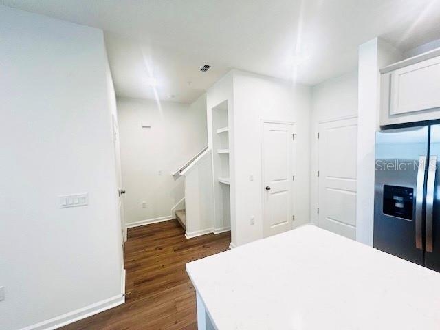 A kitchen island sits in the foreground of a room with white walls and wood flooring — 11525 STRAITS WAY, ORLANDO, FL