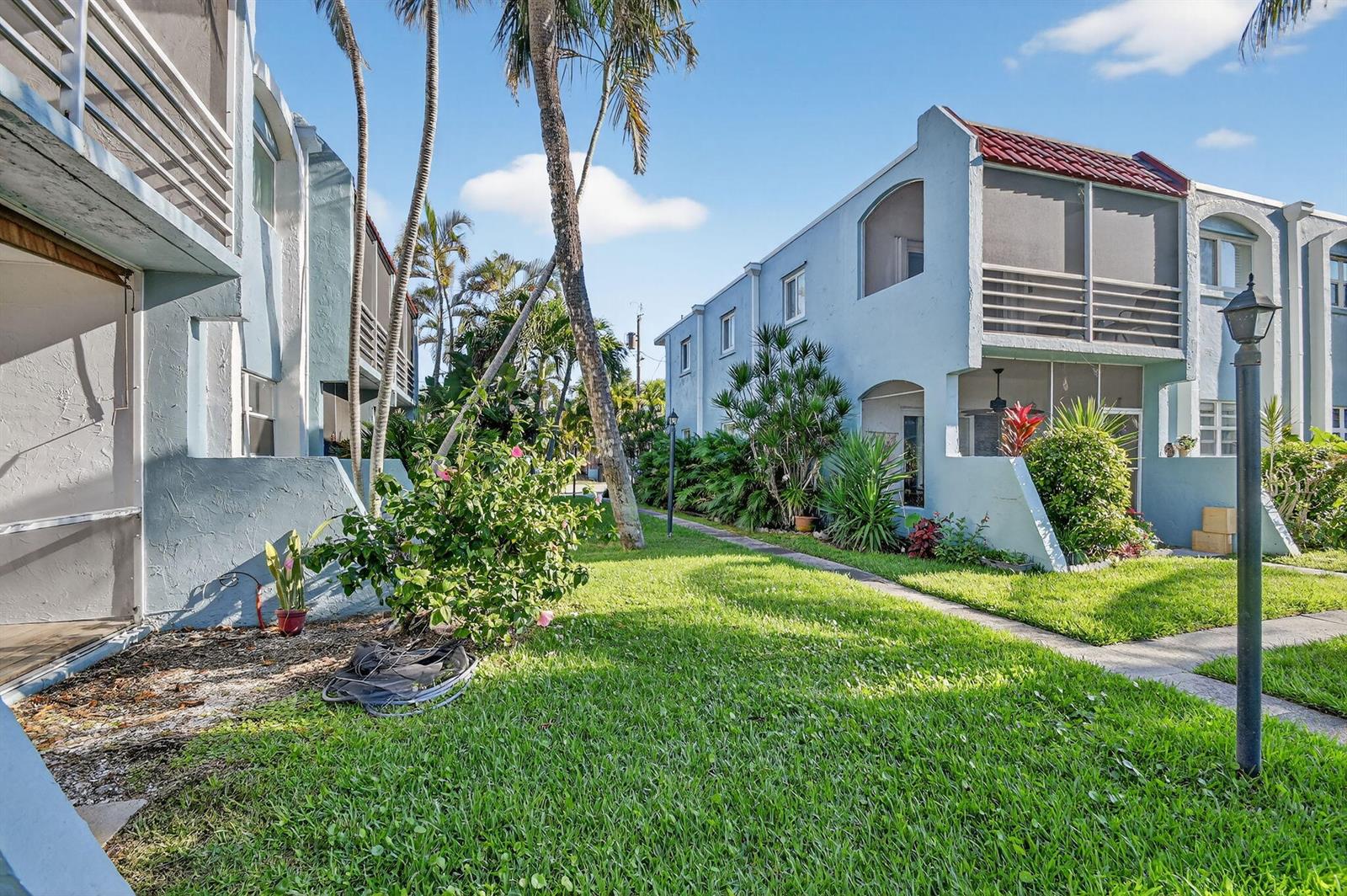 Exterior view of light blue multi-story townhomes with screened balconies and a grassy courtyard — 1432 S Lakeside Drive # 4, FL 33460, FL