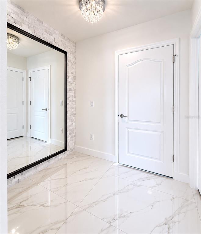 A bright entryway features white marble floors, a large wall mirror, and a crystal light fixture — 1562 CARBONDALE ROW, KISSIMMEE, FL