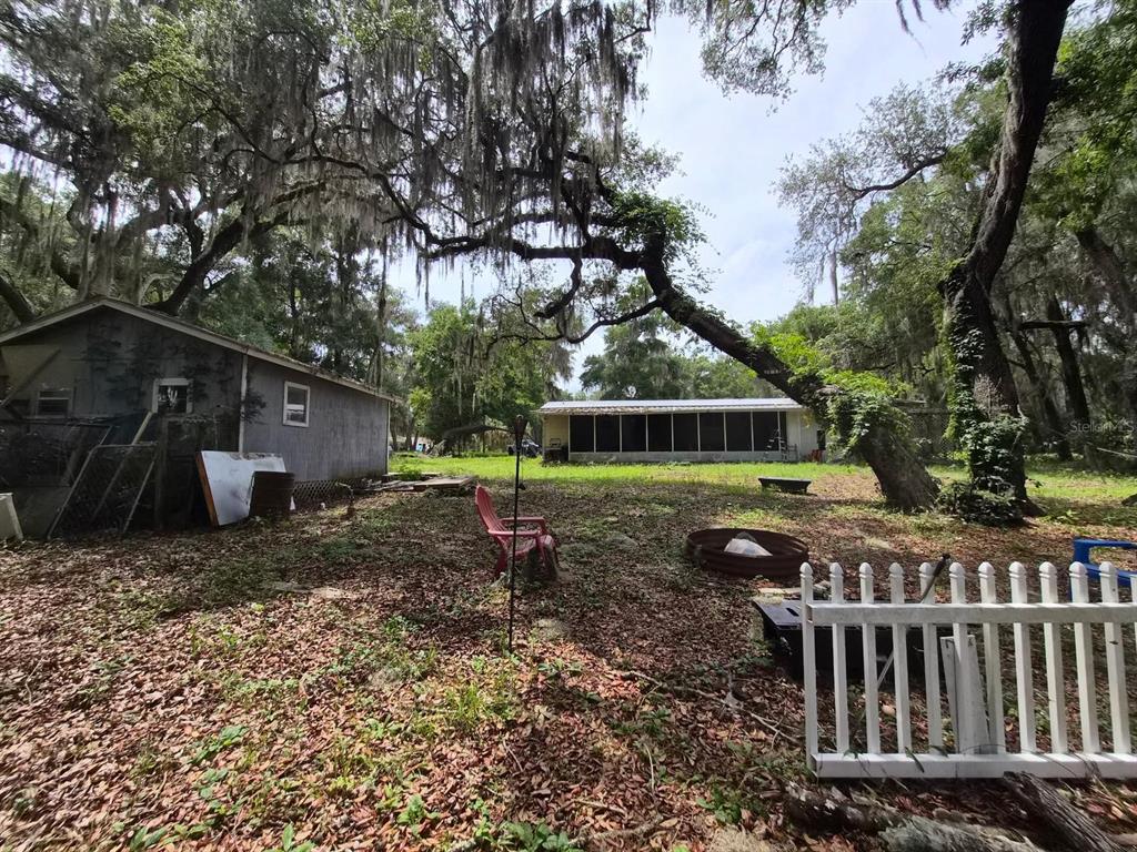 A backyard features a small shed, a screened-in porch, and large trees with Spanish moss — 14179 NE 53RD COURT ROAD, CITRA, FL