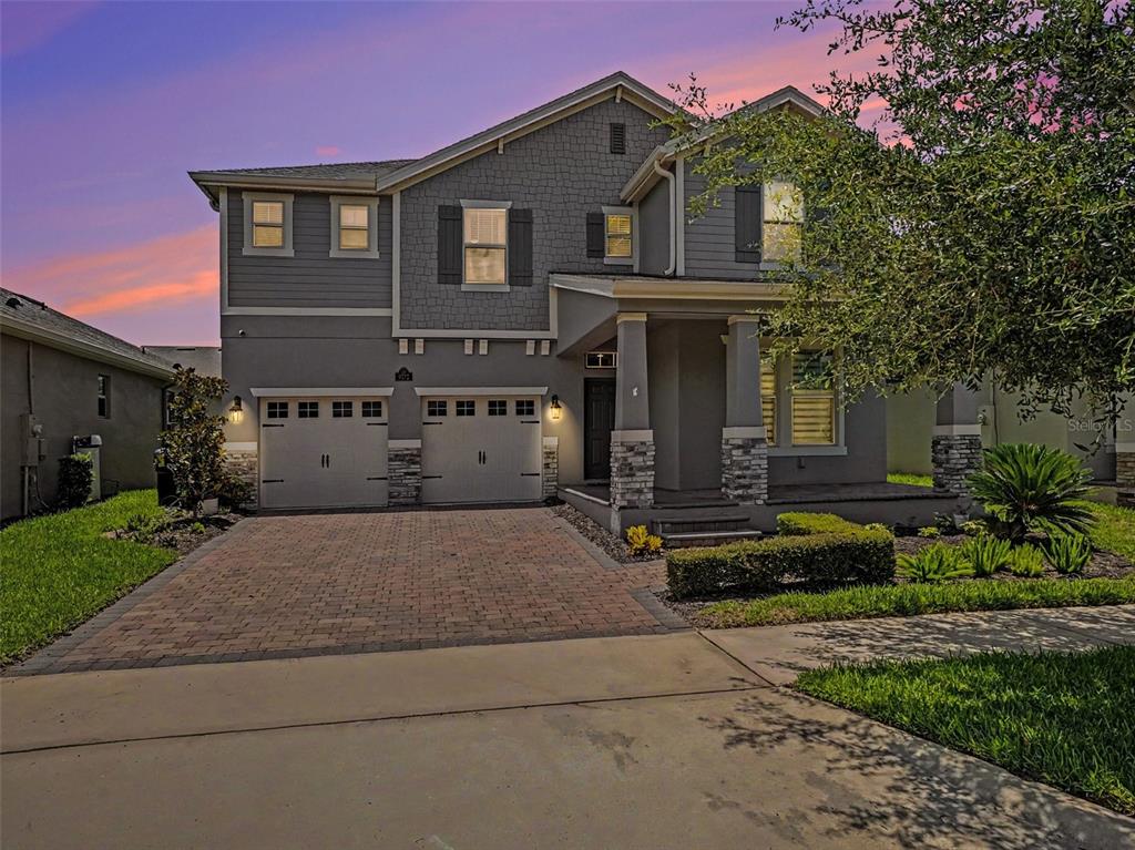 A two-story gray house with a brick driveway, two-car garage, and a covered front porch — 9572 WATERWAY PASSAGE DRIVE, WINTER GARDEN, FL