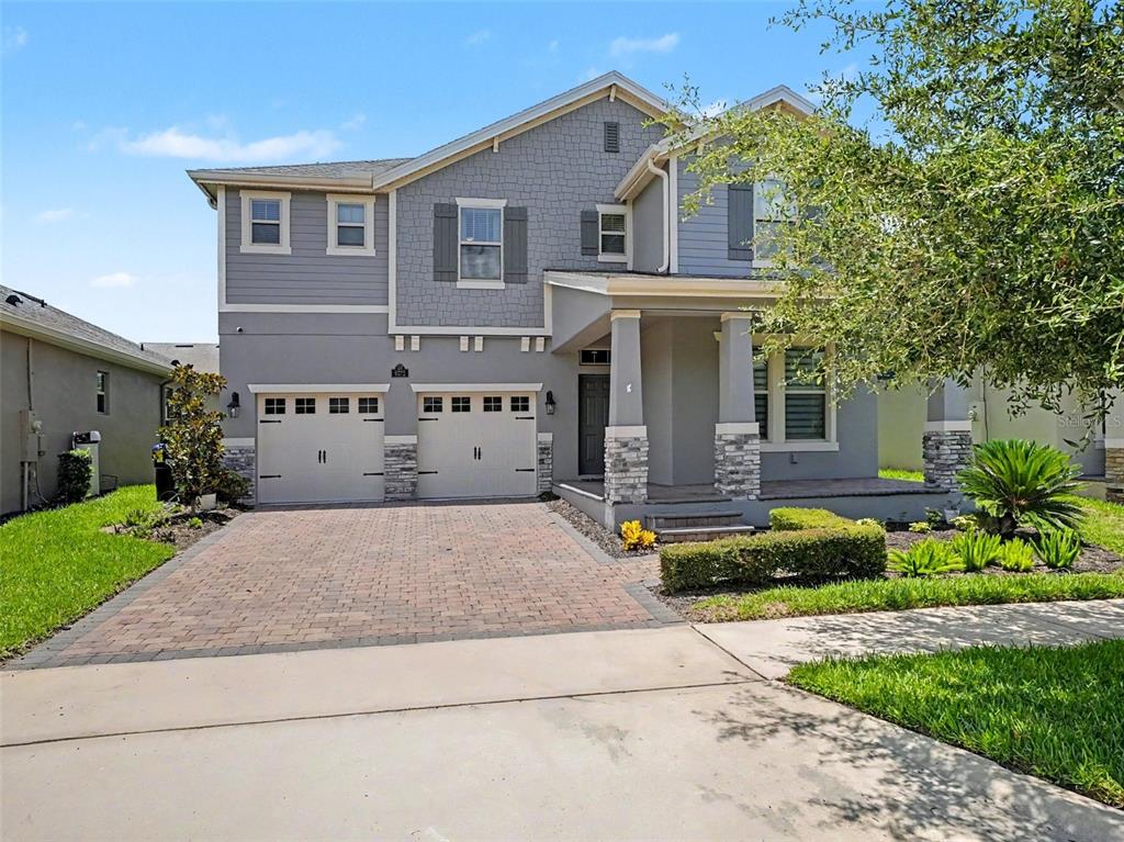 A two-story house with a gray exterior, stone accents, and a brick-paved driveway — 9572 WATERWAY PASSAGE DRIVE, WINTER GARDEN, FL