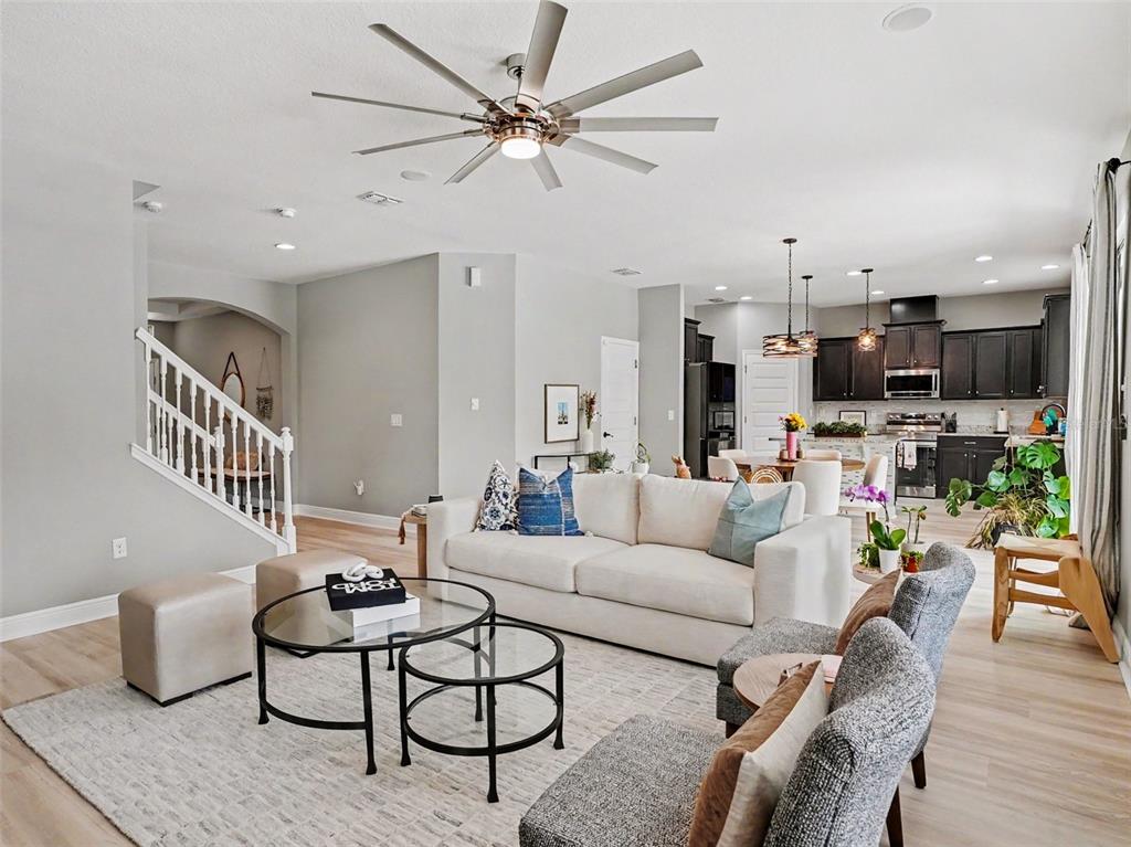A living room with a white sofa, glass coffee tables, and a large ceiling fan — 9572 WATERWAY PASSAGE DRIVE, WINTER GARDEN, FL