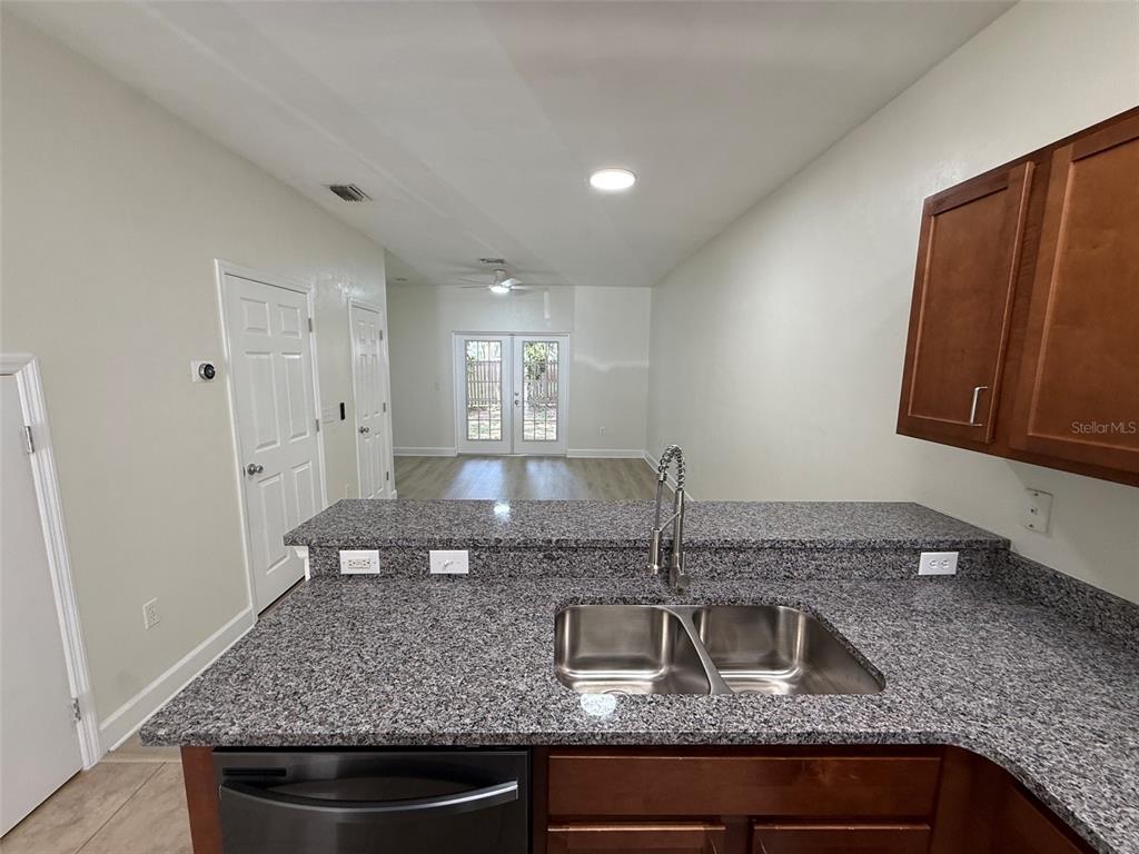 A kitchen with granite countertops and a double sink overlooks a living area with French doors — 2945 SW 35TH PLACE UNIT 132, GAINESVILLE, FL