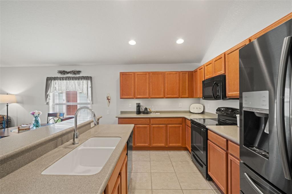 A kitchen with wood cabinets, stainless steel appliances, and a breakfast bar with a sink — 15585 LILY WOOD LANE, BROOKSVILLE, FL