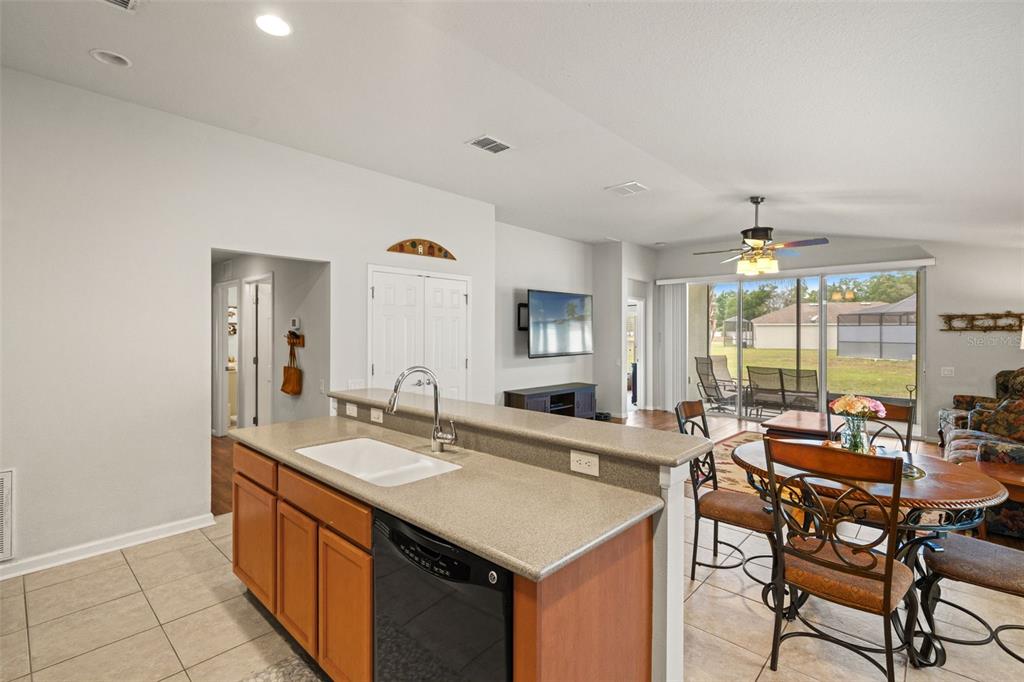 A kitchen island with a sink overlooks a dining area and a living room — 15585 LILY WOOD LANE, BROOKSVILLE, FL