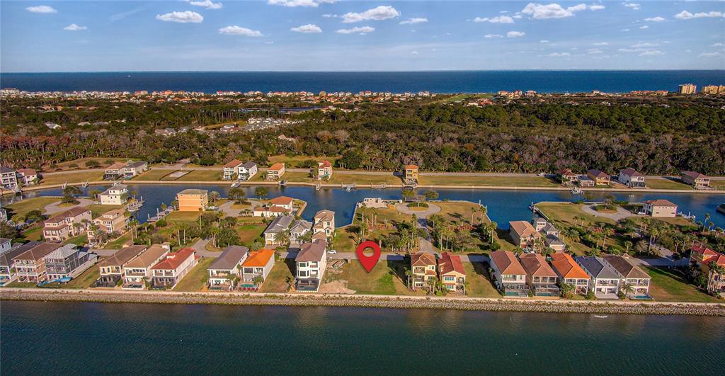 An aerial view shows a vacant waterfront lot marked with a red pin among houses — 276 YACHT HARBOR DRIVE, PALM COAST, FL