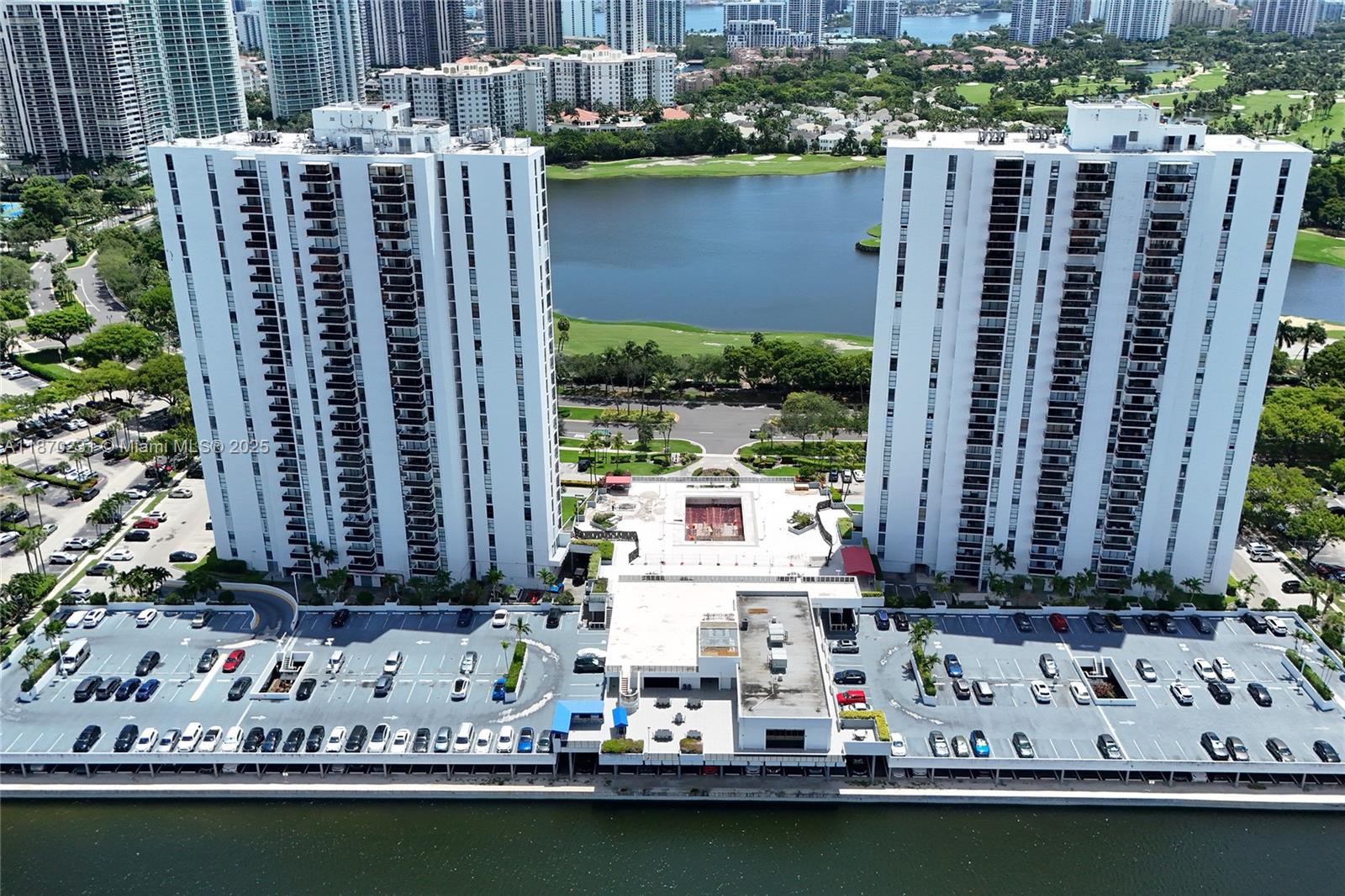 An aerial view shows two tall white residential towers flanking a parking lot and pool deck — 3675 N Country Club Dr # 204, Aventura FL 33180, AVENTURA, FL