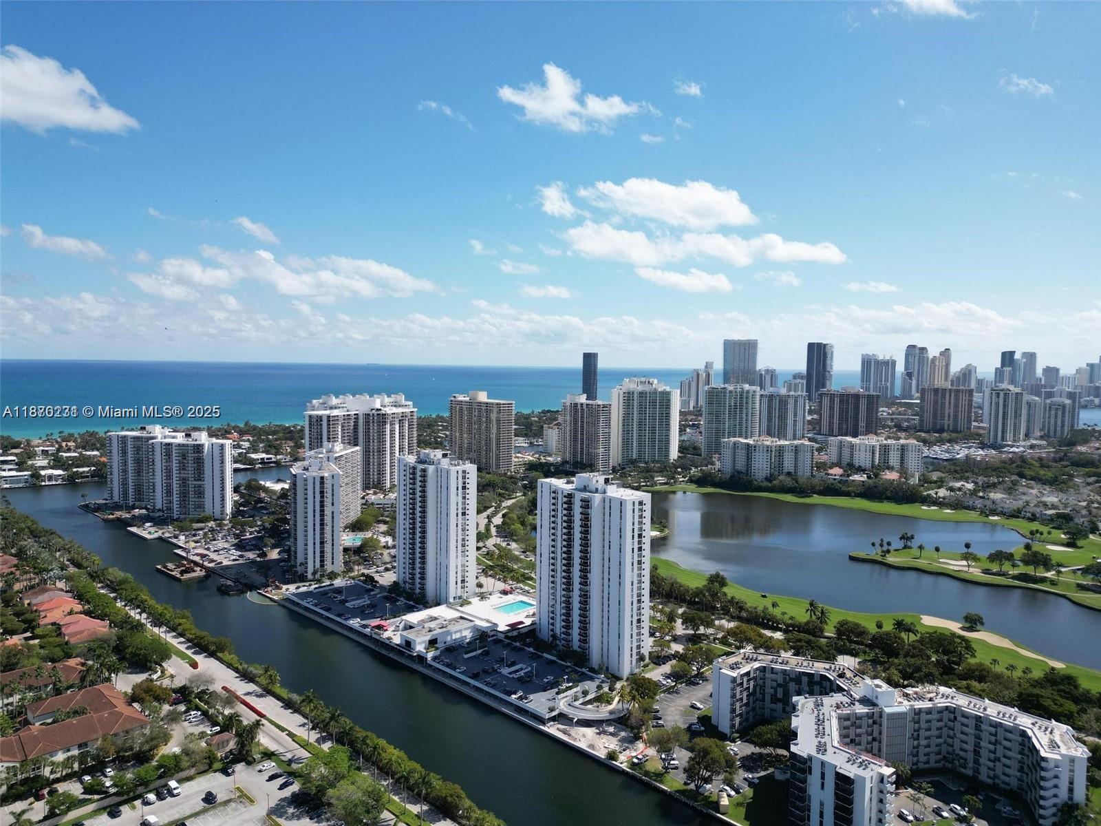 An aerial view shows high-rise residential buildings situated along a canal and a lake — 3675 N Country Club Dr # 204, Aventura FL 33180, AVENTURA, FL