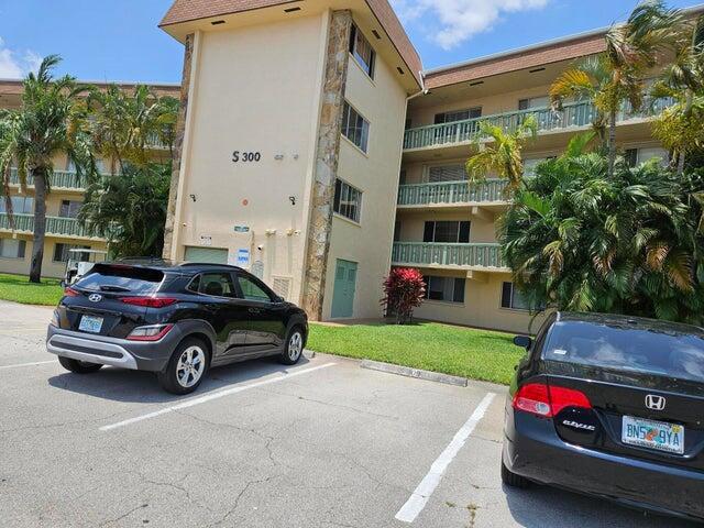 A black Hyundai and a black Honda are parked in front of a multi-story apartment building — 300 Village Green Circle S # 209, Palm Springs FL 33461, PALM SPRINGS, FL