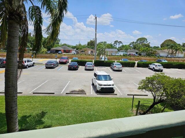An elevated view of a parking lot with several cars parked in front of residential houses — 300 Village Green Circle S # 209, Palm Springs FL 33461, PALM SPRINGS, FL