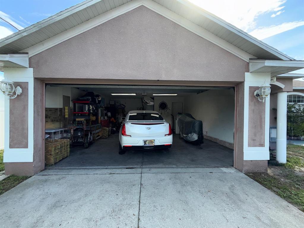 A white car is parked inside an open two-car garage attached to a house — 8414 BAY DRIVE, SPRING HILL, FL
