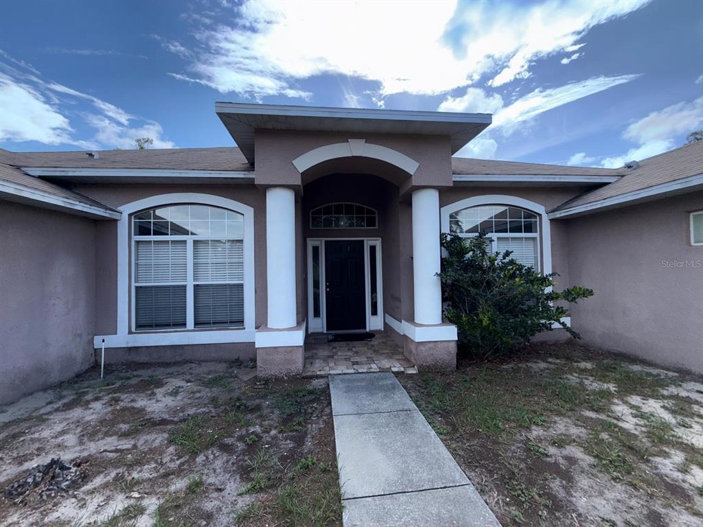 A single-story house exterior features a covered entryway with two white columns and arched windows — 8414 BAY DRIVE, SPRING HILL, FL