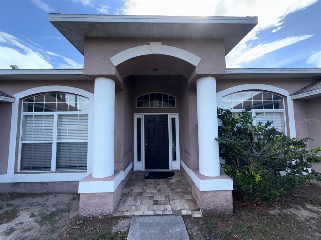 The front entrance of a house features two large white columns and a black door — 8414 BAY DRIVE, SPRING HILL, FL