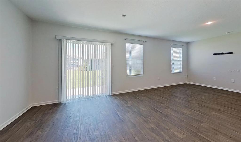 An empty room features light gray walls, wood-look flooring, vertical blinds, and two windows — 5471 HOLLOW BIRCH DRIVE, JACKSONVILLE, FL