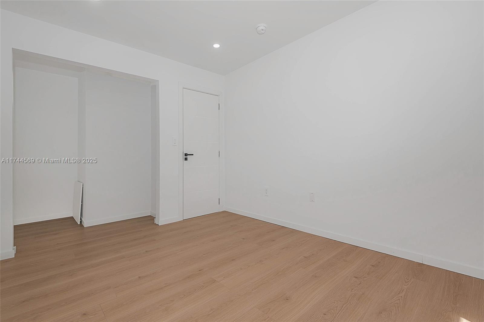 A modern kitchen features white cabinetry, marble-patterned countertops, stainless steel appliances, and open wooden shelving — 1985 Calais # 3, Miami Beach FL 33141, MIAMI BEACH, FL