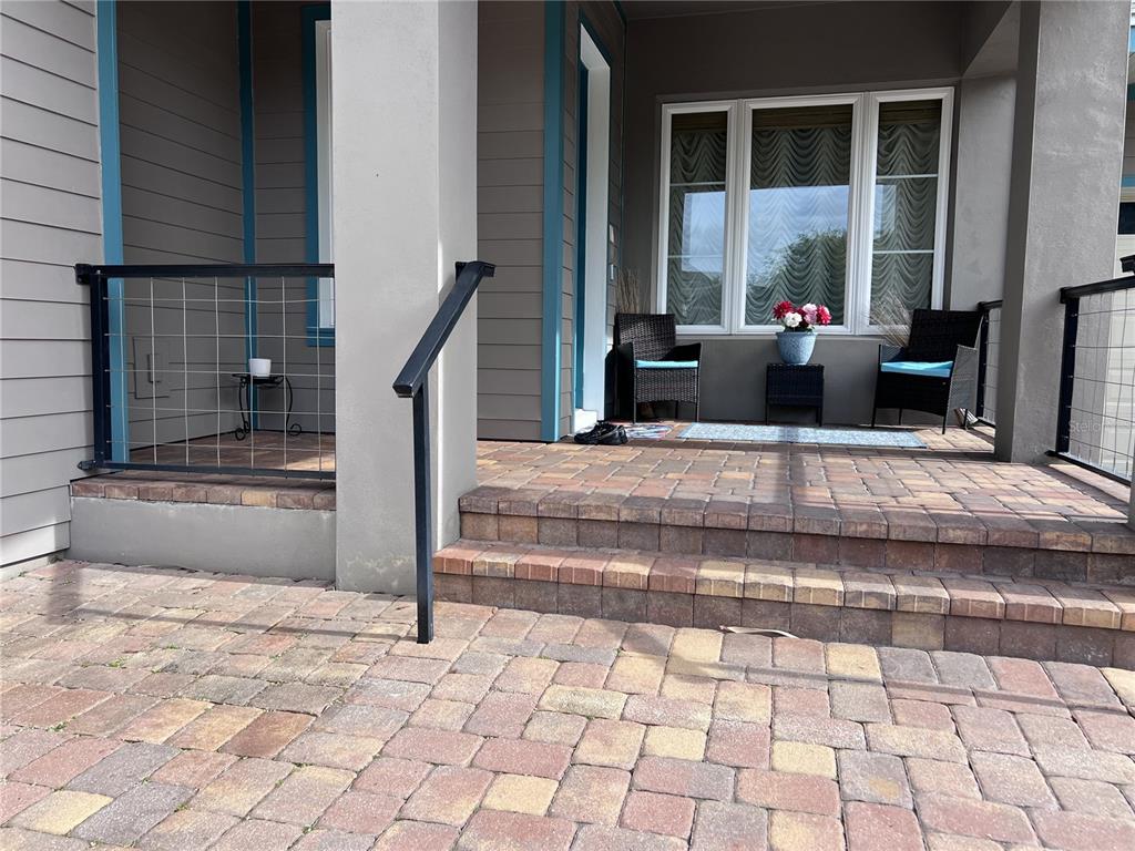 A paved front porch features a metal railing, two wicker chairs, and a small table — 9406 DUGARD COURT, ORLANDO, FL