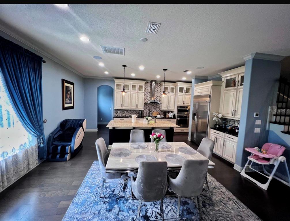 A dining area with a marble table sits in front of an open-concept kitchen — 9406 DUGARD COURT, ORLANDO, FL