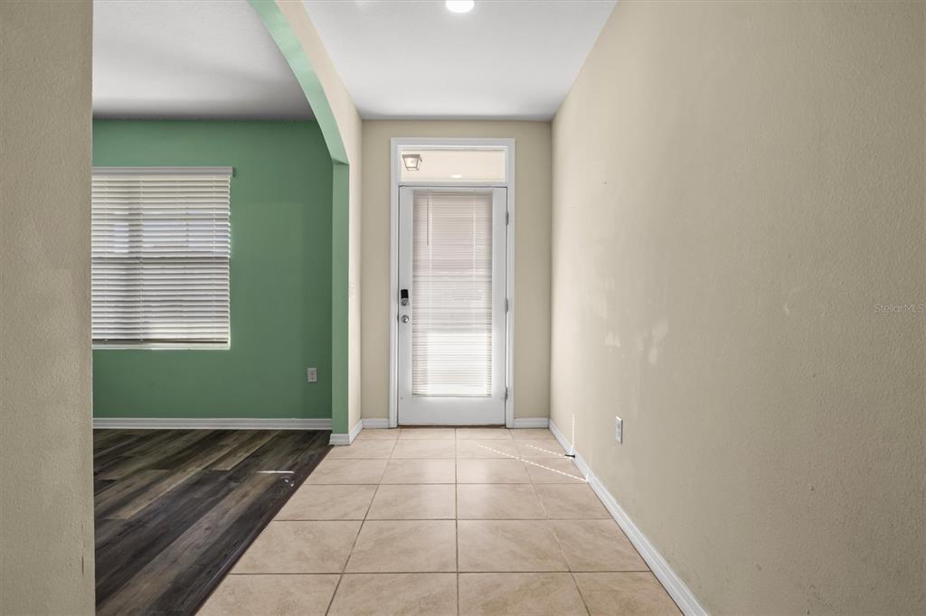 An entryway features beige tile flooring, a glass-paneled door, and an adjacent room with green walls — 323 HARBOUR WAY, MULBERRY, FL