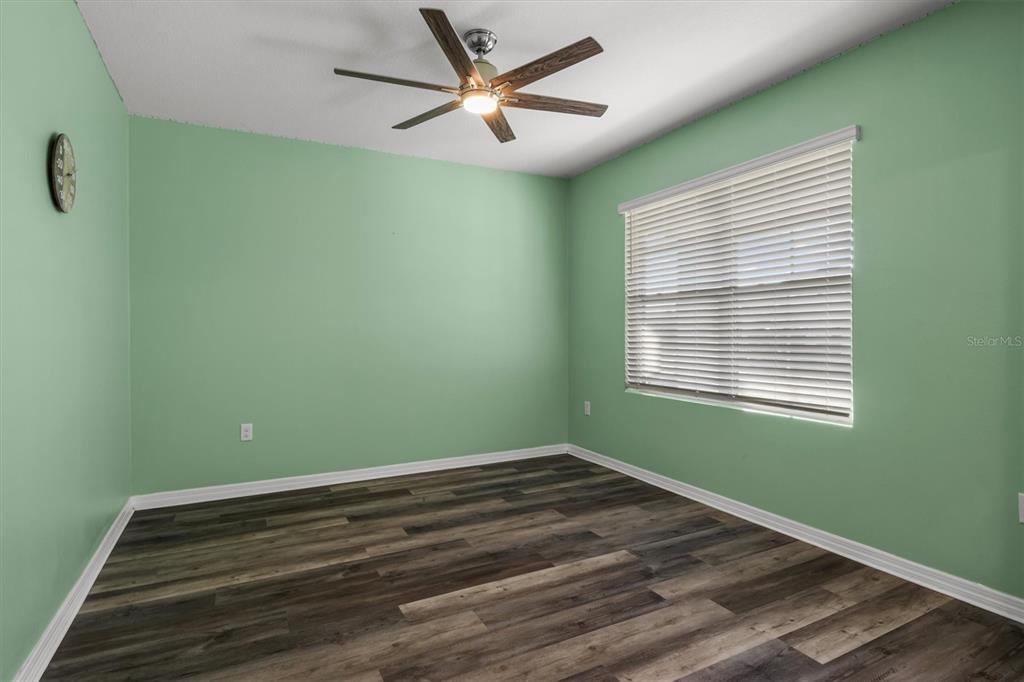An empty bedroom features light green walls, wood-look flooring, a ceiling fan, and window blinds — 323 HARBOUR WAY, MULBERRY, FL