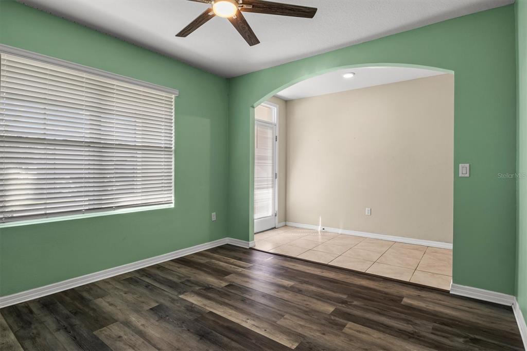 A room with green walls, wood-look flooring, and an arched opening to a tiled area — 323 HARBOUR WAY, MULBERRY, FL