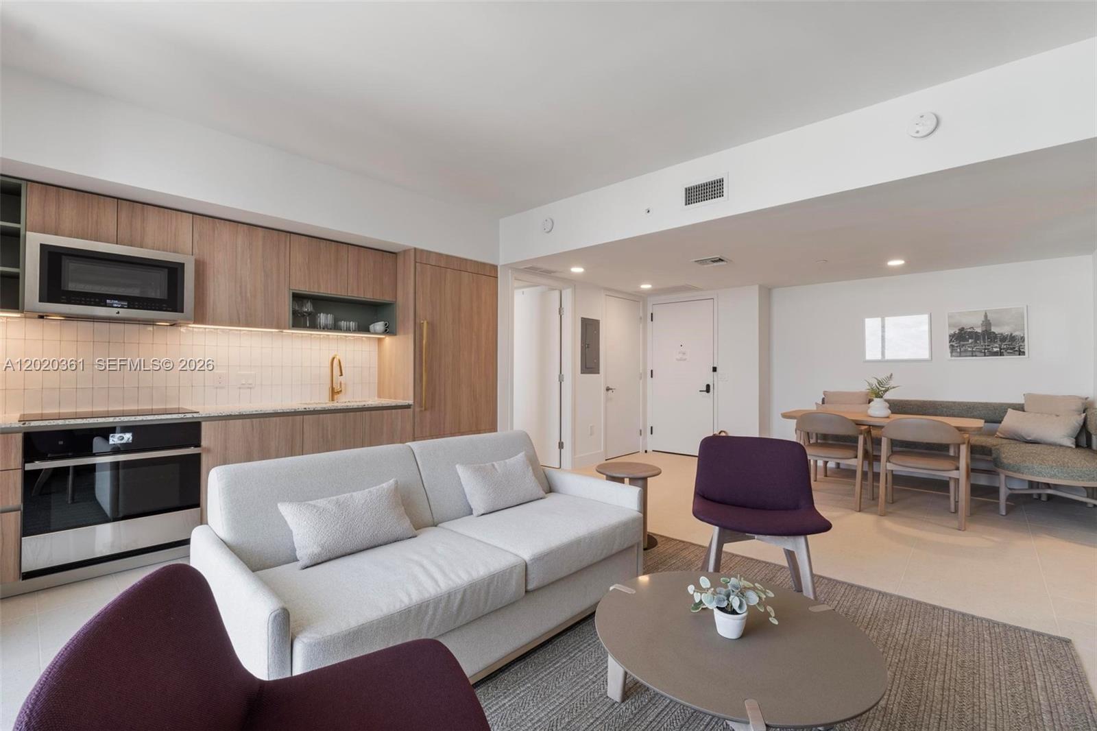 This open-concept living area features a modern kitchen, a light-colored sofa, and a dining nook — 601 ne 1st ave # 2801, Miami FL 33132, MIAMI, FL