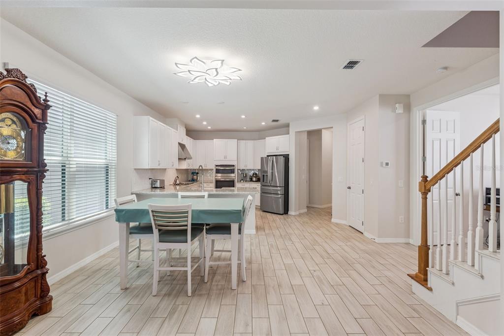 A kitchen and dining area with white cabinets, stainless steel appliances, and wood-look tile flooring — 1287 VERDANT GLADE PLACE, WINTER PARK, FL