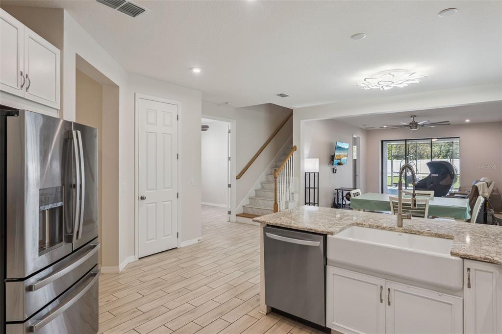 A kitchen with stainless steel appliances, white cabinets, and granite countertops overlooks a dining area — 1287 VERDANT GLADE PLACE, WINTER PARK, FL