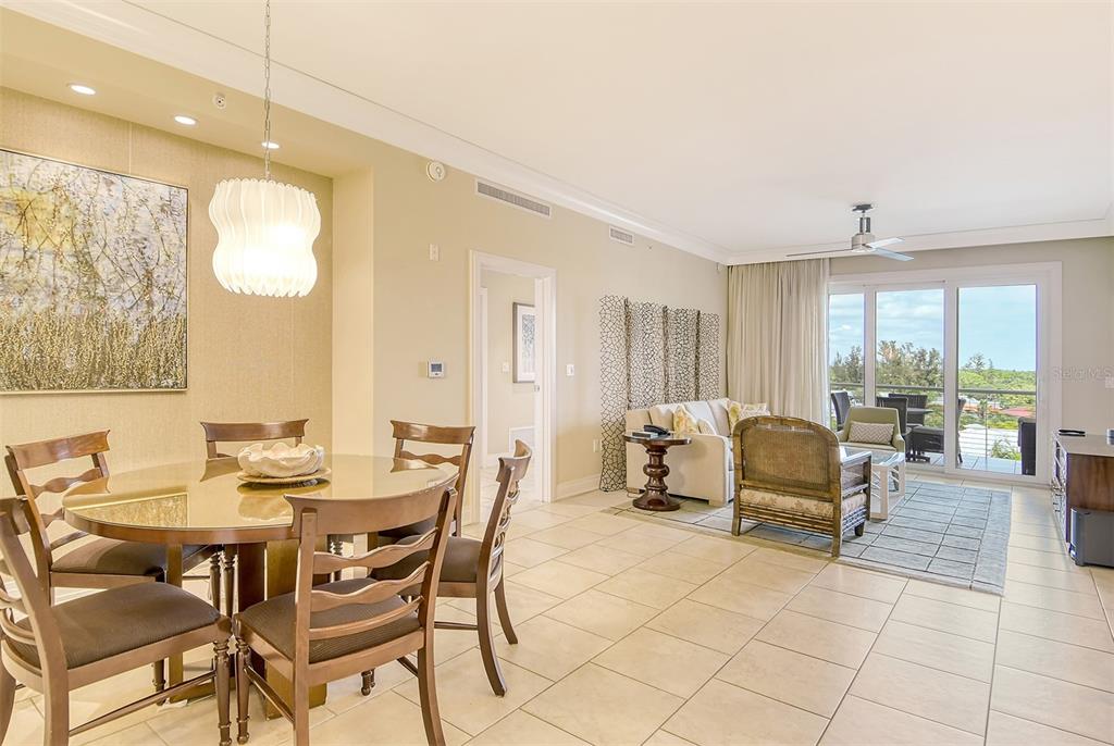 A dining area and living room with tile floors, neutral walls, and a balcony view — 915 SEASIDE DRIVE UNIT 607, Weeks 14-15, SARASOTA, FL