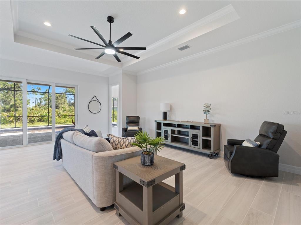 A living room features a tray ceiling, a large ceiling fan, and light-colored tile flooring — 13356 RAYBURN LANE, PORT CHARLOTTE, FL