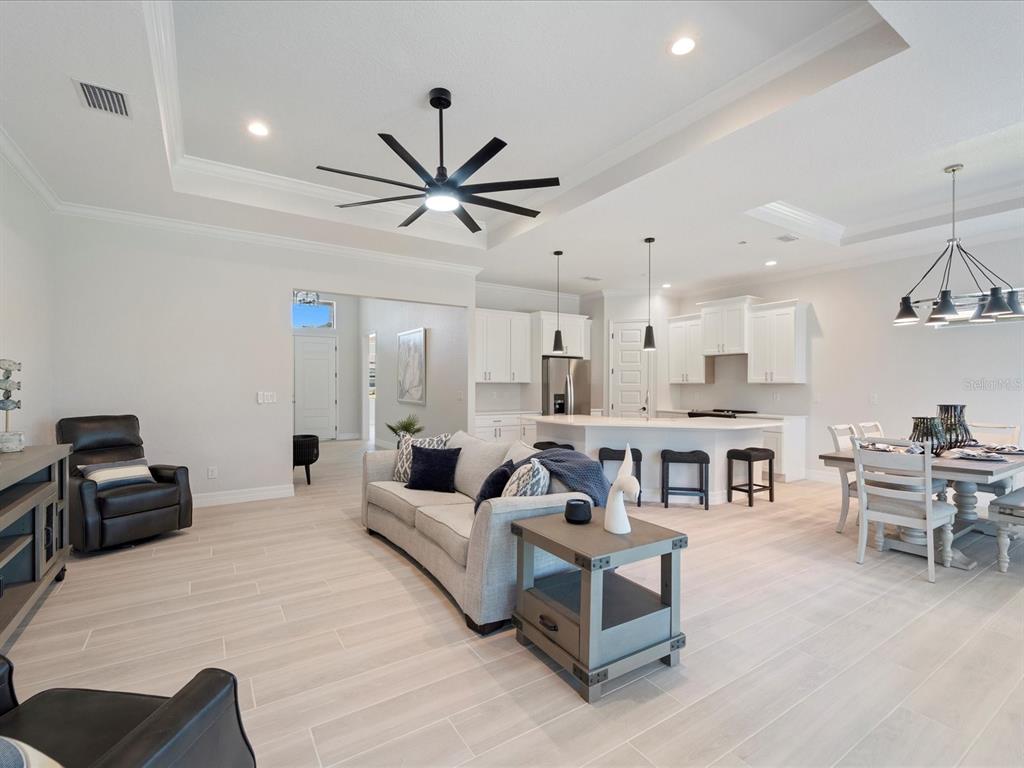 An open-concept living room and kitchen feature light wood-look tile flooring and white cabinetry — 13356 RAYBURN LANE, PORT CHARLOTTE, FL