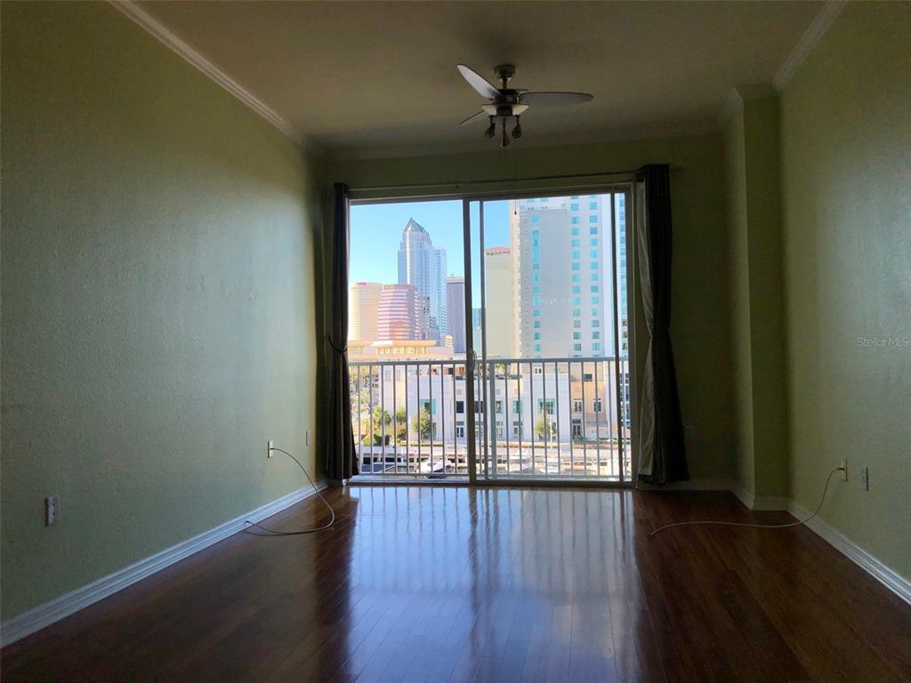 An empty room with hardwood floors, a ceiling fan, and a balcony overlooking city buildings — 700 S HARBOUR ISLAND BOULEVARD UNIT 523, TAMPA, FL