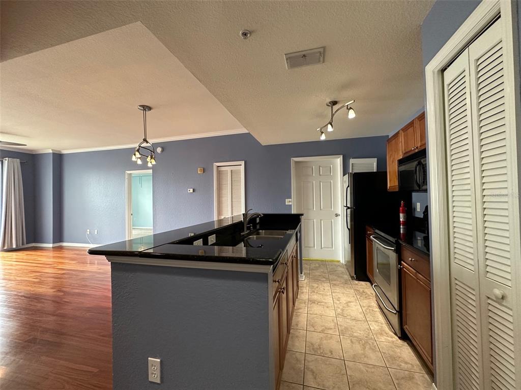 A kitchen with dark countertops and wood cabinets opens to a living area with flooring — 700 S HARBOUR ISLAND BOULEVARD UNIT 523, TAMPA, FL