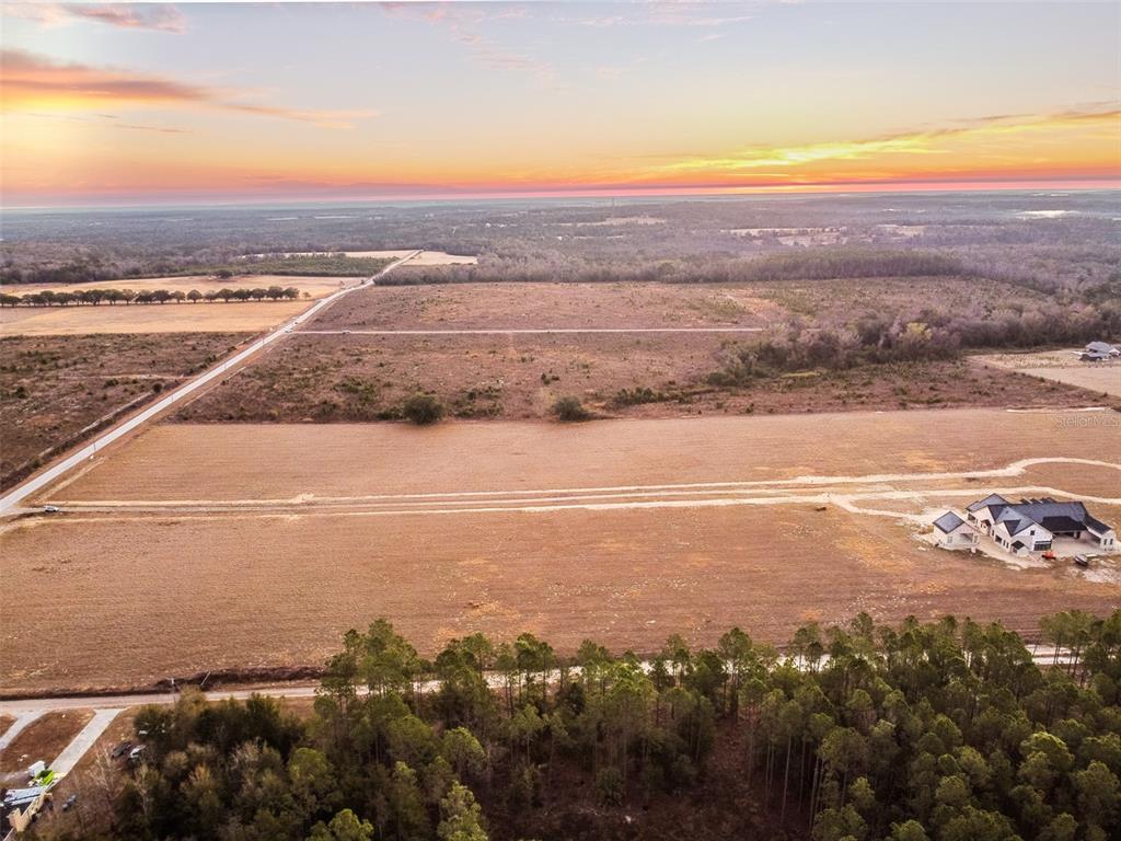 An aerial view shows a large, cleared plot of land with a single house under construction — 4237 ROYAL SKY (LOT 5) COURT, BROOKSVILLE, FL