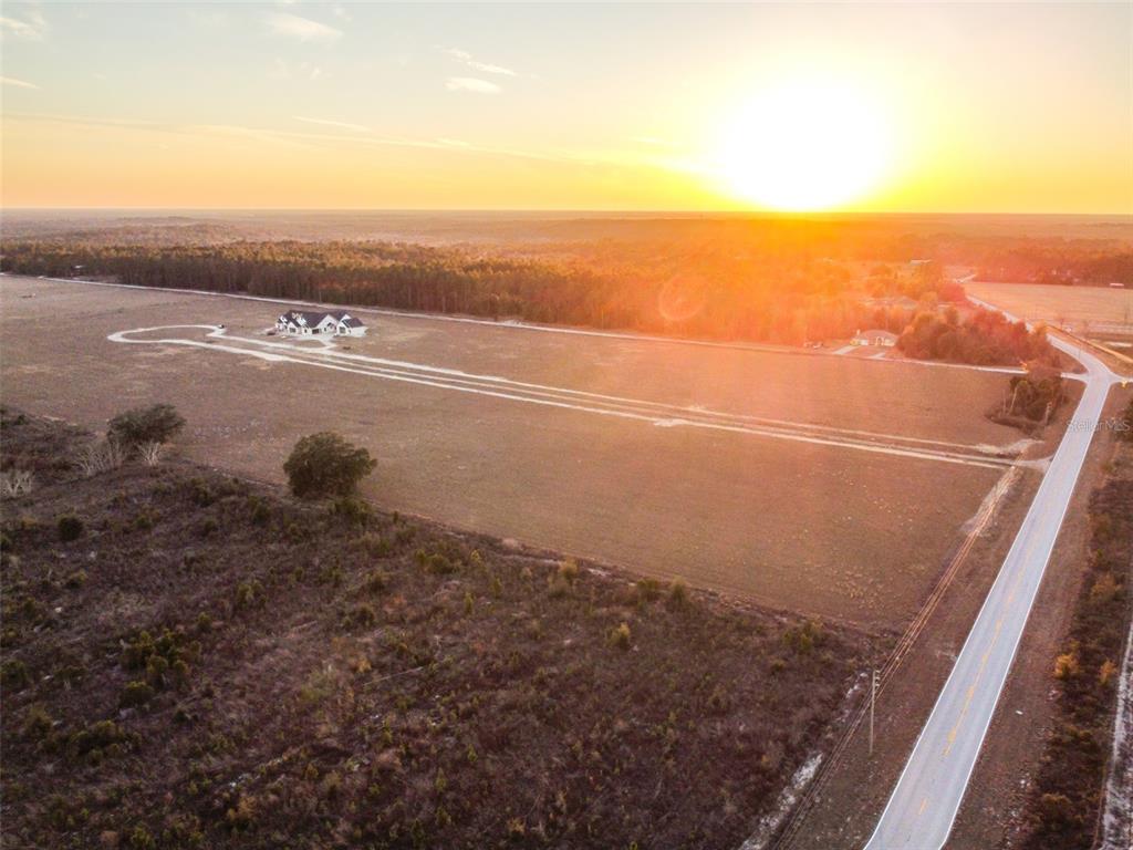 An aerial view shows a house on a large, open field at sunset — 4237 ROYAL SKY (LOT 5) COURT, BROOKSVILLE, FL
