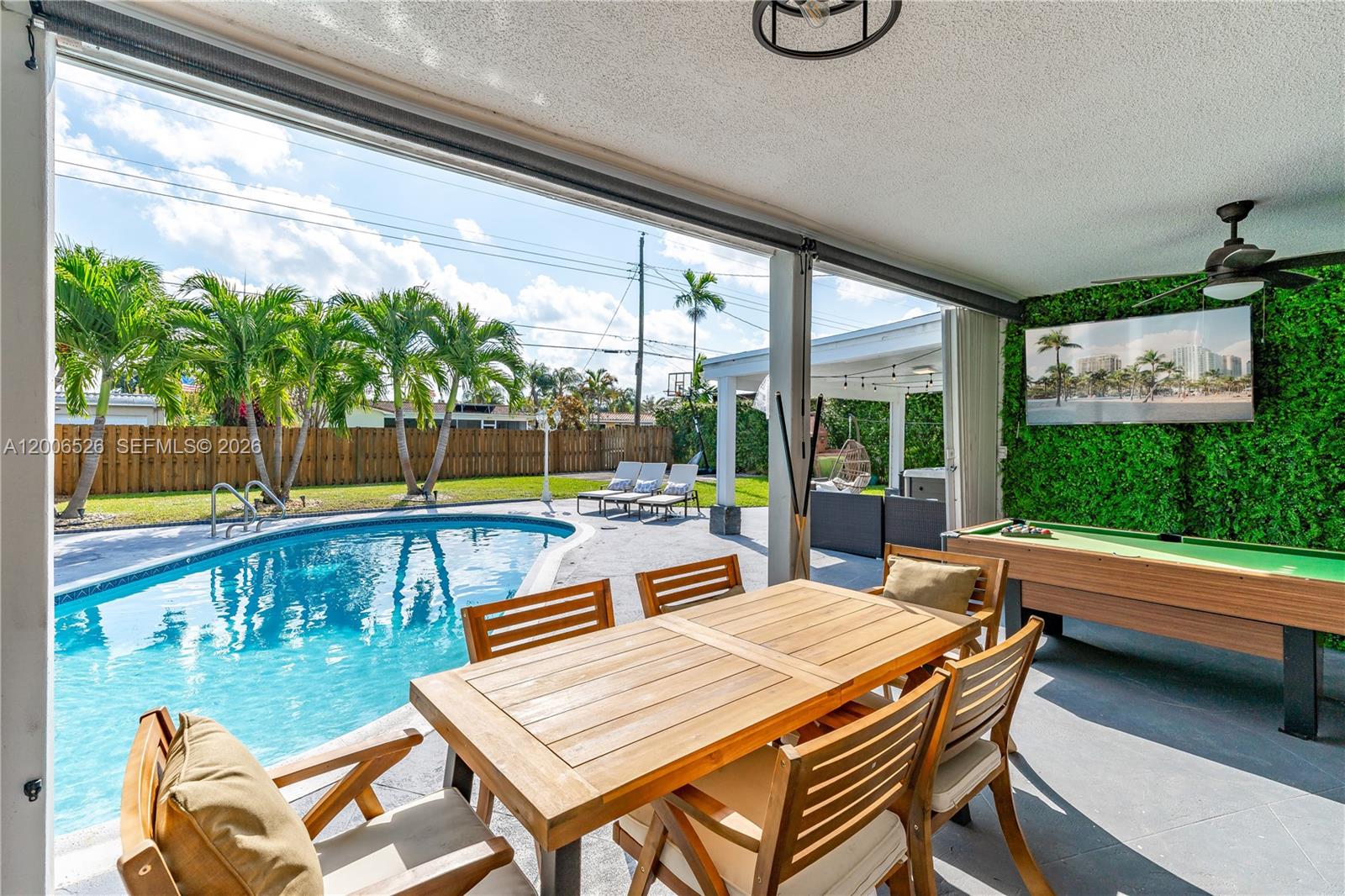 A covered patio features a dining set, pool table, and view of a backyard pool — 4212 Van Buren St # 0, Hollywood FL 33021, HOLLYWOOD, FL