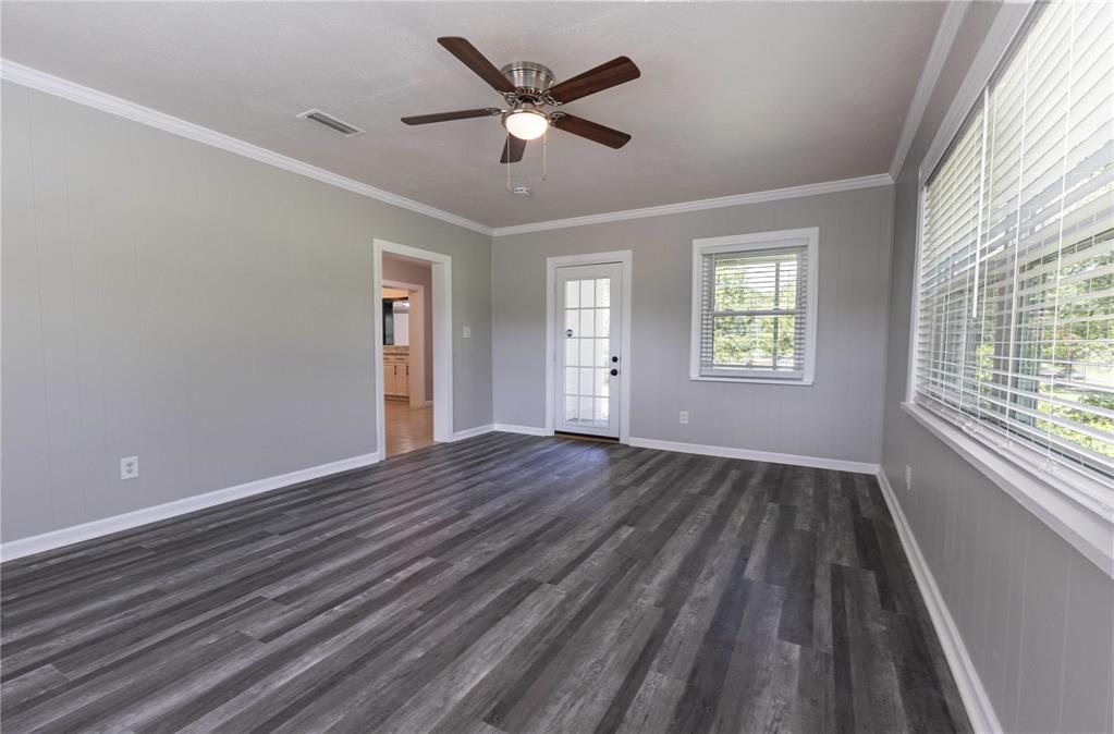 A living room with gray walls, wood-look plank flooring, a ceiling fan, and a door — 11302 SE HIGHWAY 42 HIGHWAY, SUMMERFIELD, FL