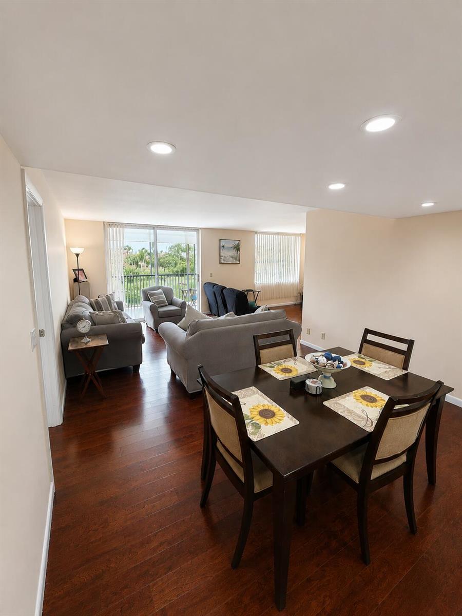 A dining area with a dark wood table leads into a living room with hardwood floors — 6500 NW 2nd Avenue # 512, Boca Raton FL 33487, BOCA RATON, FL