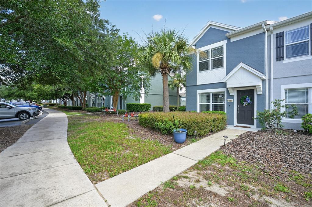 A two-story blue townhouse with a front walkway, small garden, and a palm tree — 4908 SW 45TH CIRCLE, OCALA, FL
